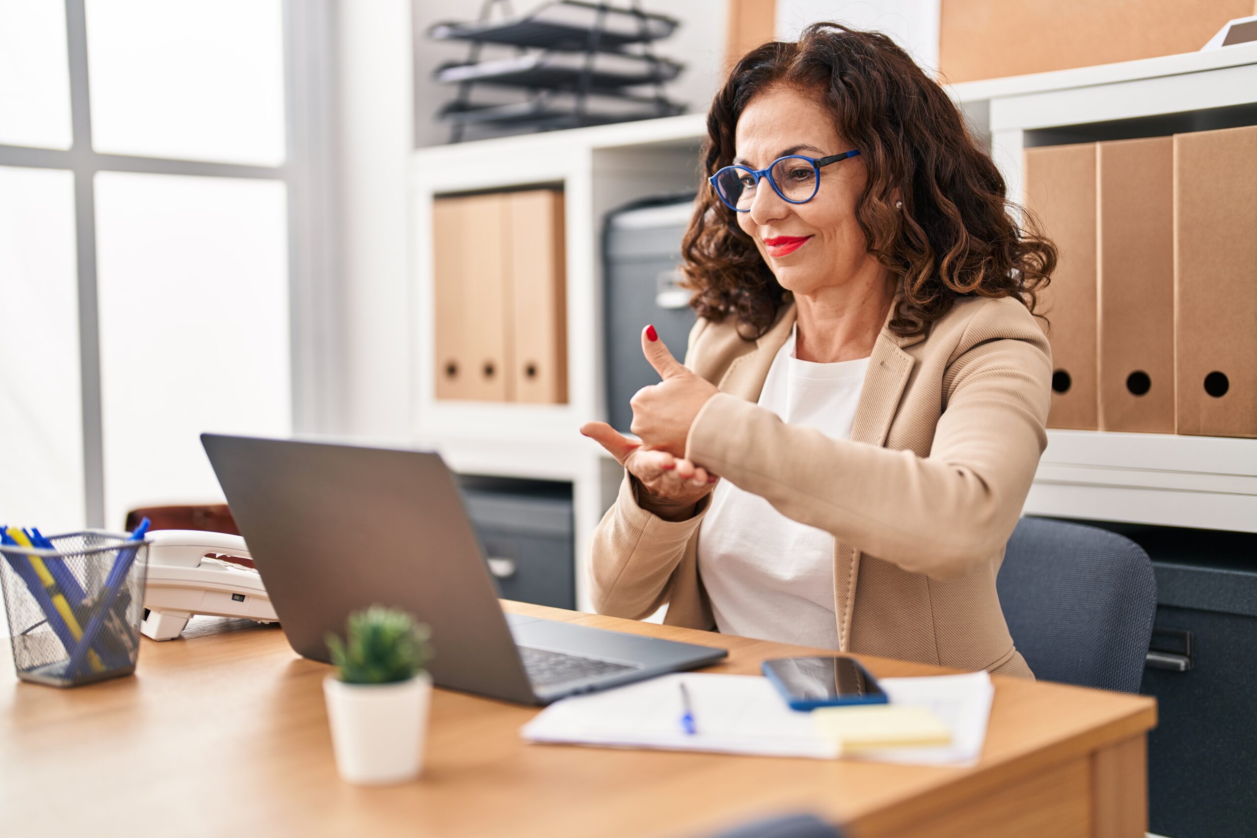 Middle age hispanic woman doing video call using sign language at the office